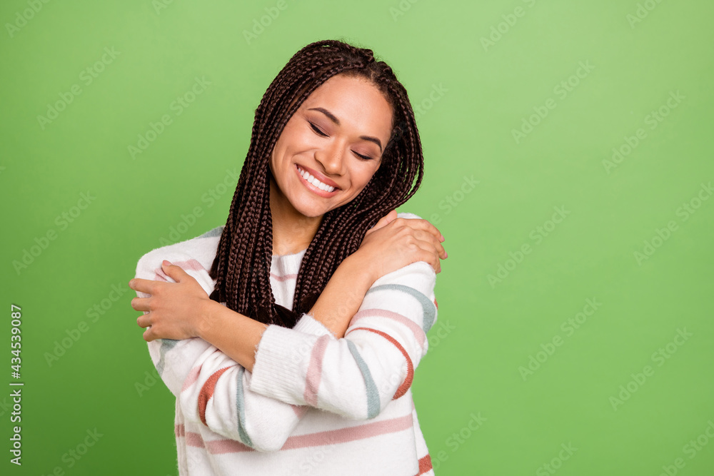 Photo of happy nice charming dark skin woman hug herself good mood isolated on green color background Photo of happy nice charming dark skin woman hug herself good mood isolated on green color background