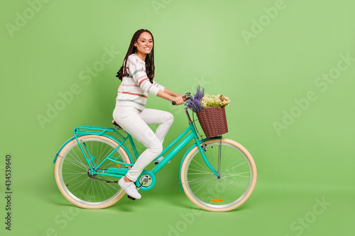 Fototapeta Naklejka Na Ścianę i Meble -  Full size profile side photo of young black girl happy positive smile ride bicycle vehicle trip isolated over green color background