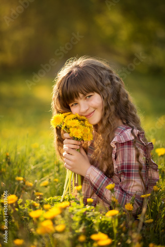 Photo of a girl with long hair in a meadow with dandelions.
