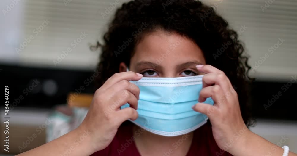 Little girl putting covid face mask. Preteen child wearing surgical mask Little girl putting covid face mask. Preteen child wearing surgical mask