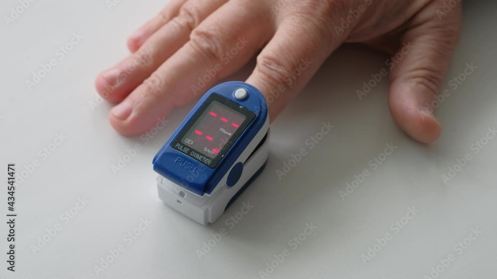 A pulse oximeter on a persons finger measures the oxygen level in the blood. Health care and medicine concept