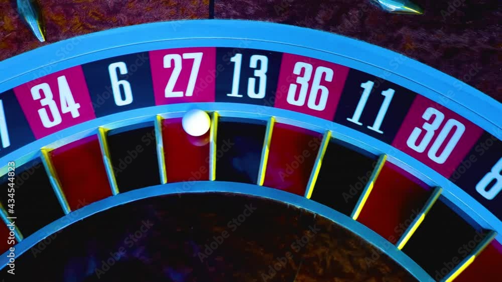 Top view of part of gambling roulette in casino with white ball on 27 red. The roulette wheel spins in slow motion, close up numbers. Gambling, betting, chance to win.