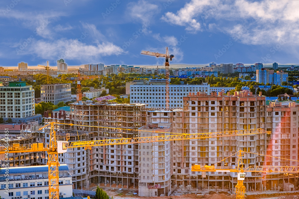 Upper View of New Mass- Construction Site with Buildings and Cranes Against Sky with Clouds.