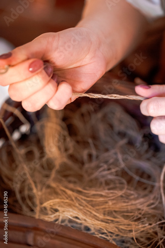 Closeup of Hands of Young Caucasian Woman Spinning Yarn in Retro Dress In Rural Environment. photo