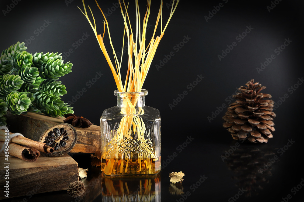 The luxury scented aroma room fresherner reed diffuser sticks glass bottle is on the black table to creat relax ambient with background of black cement wall in the living room