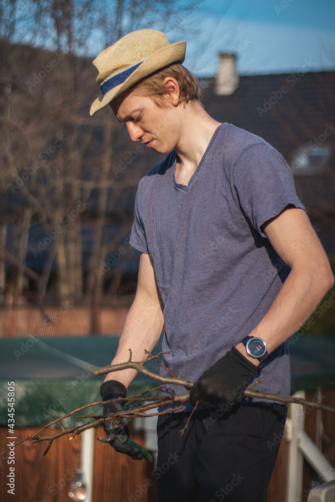 Hardworking man in work clothes uses loppers to split wood into smaller sticks to fit into the kiln for burning. Work in the garden. Grooming the plot. Beautifying the orchards Hardworking man in work clothes uses loppers to split wood into smaller sticks to fit into the kiln for burning. Work in the garden. Grooming the plot. Beautifying the orchards