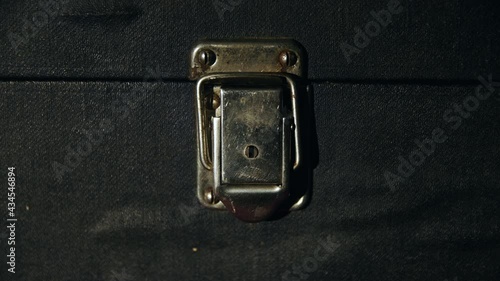 Caucasian man by hand closes an old vintage metal rusty lock on a dirty antique suitcase close up