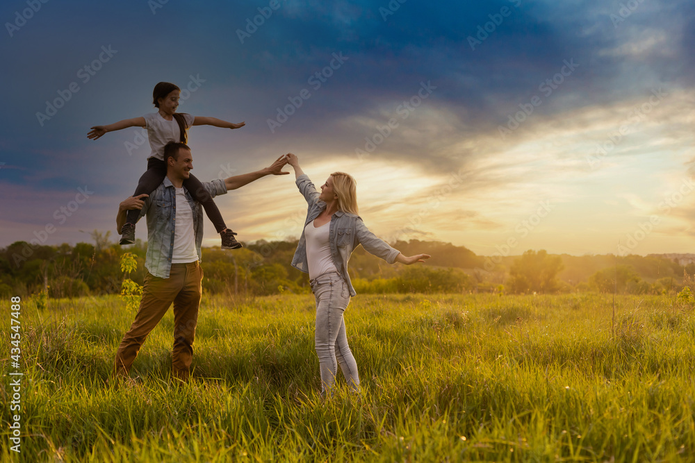 Happy family in the park evening light. The lights of a sun. Mom, dad and baby happy walk at sunset. The concept of a happy family Happy family in the park evening light. The lights of a sun. Mom, dad and baby happy walk at sunset. The concept of a happy family