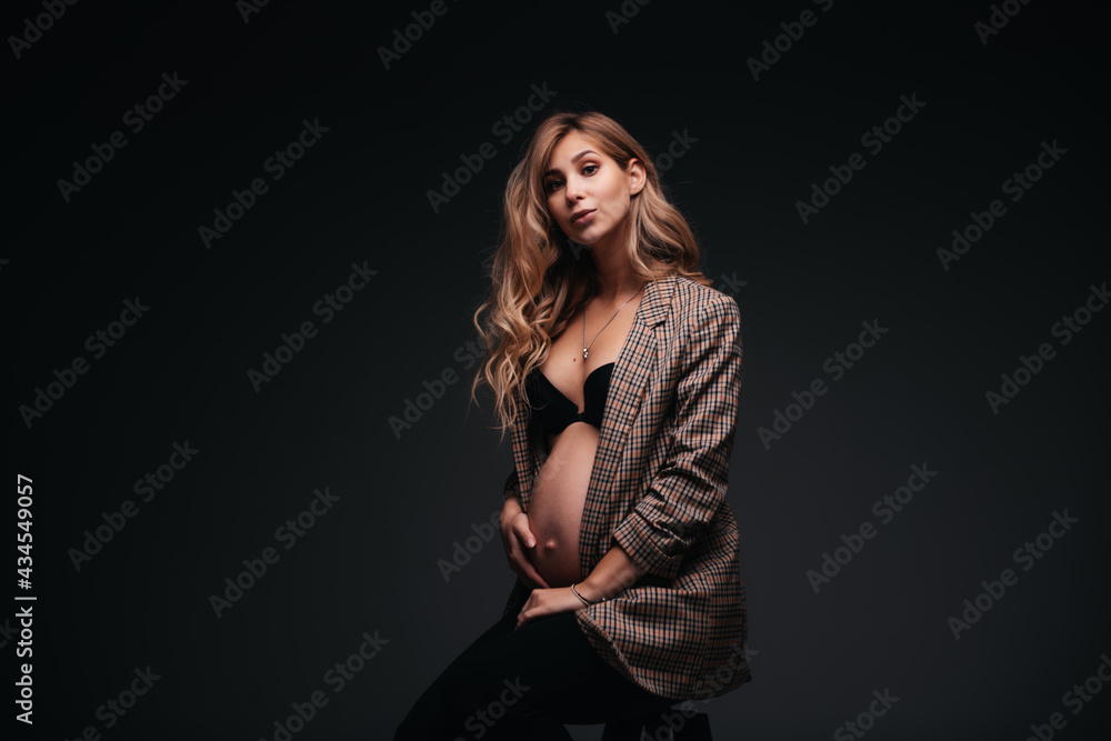 Young beautiful pregnant woman in jacket on black background Young beautiful pregnant woman in jacket on black background