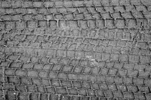 Tyre tracks on sandy dirty road in black and white.