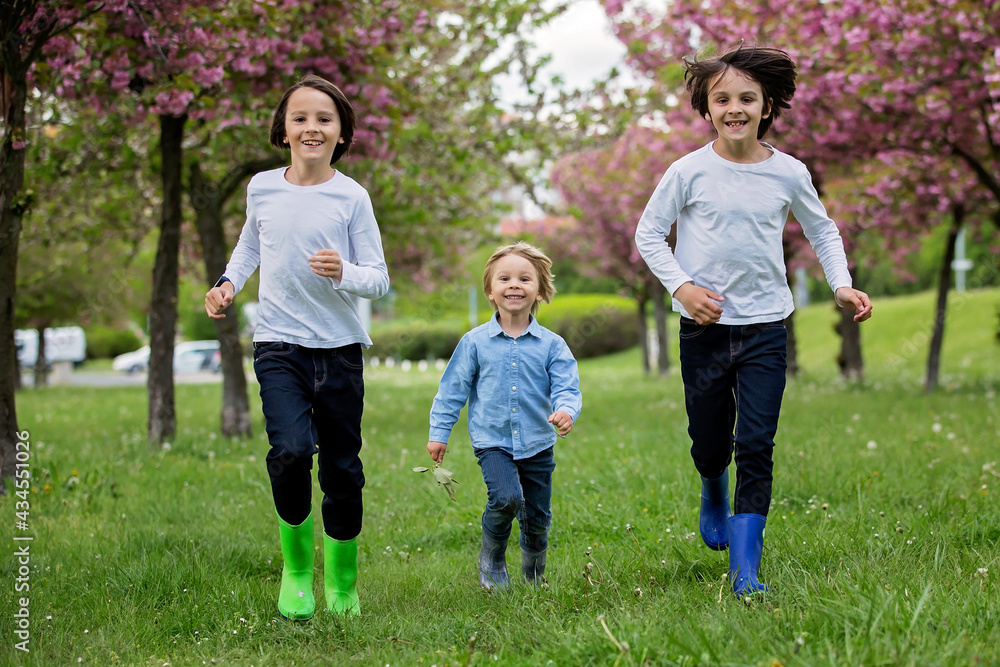 Happy children of different age groups, running together in the park, springtime, having fun