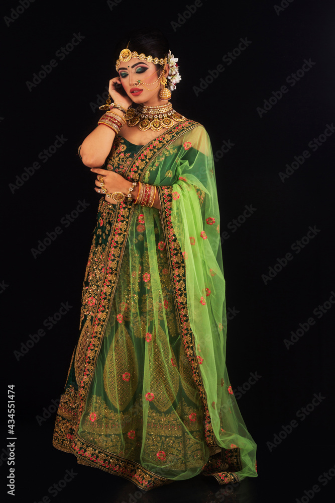 Woman in bridal green sari and gold jewelry looking down