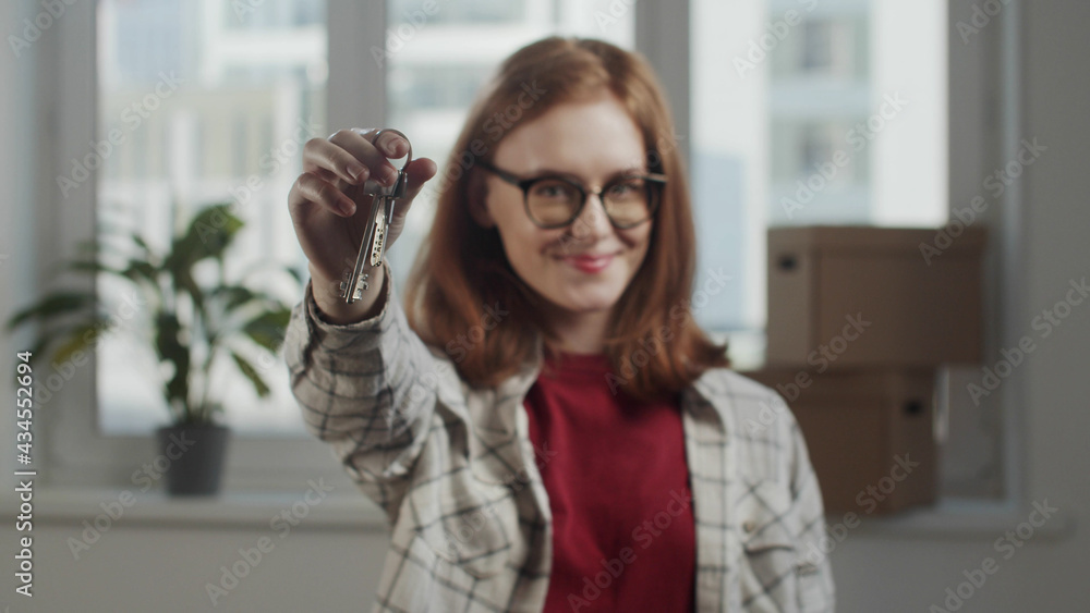 Young woman shakes apartment keys and smiles in slow motion