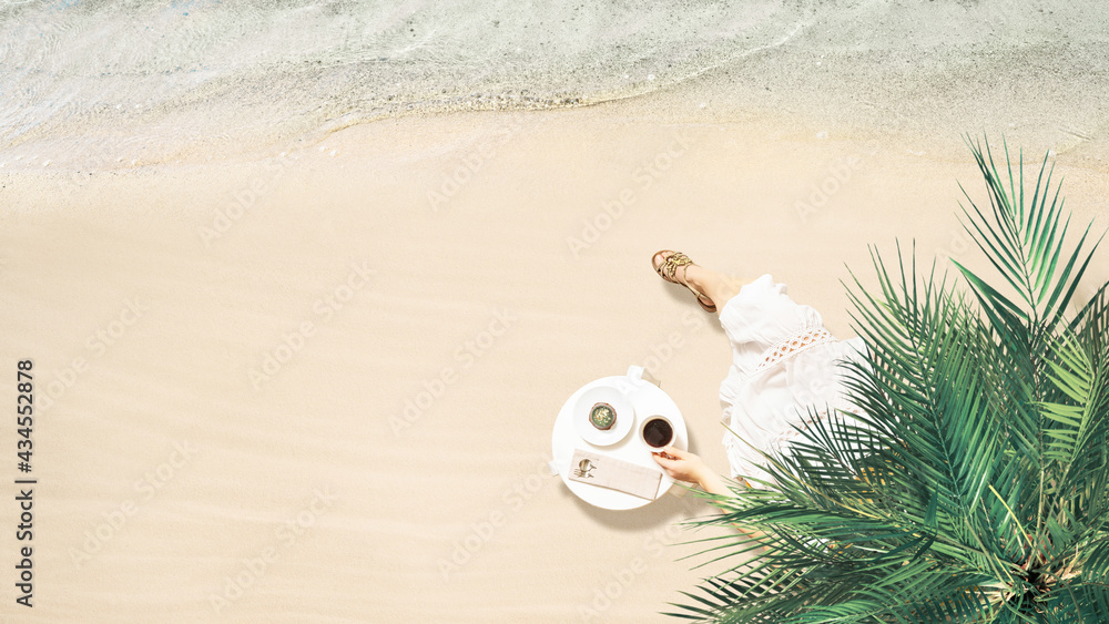 Obraz premium Woman drinking hot coffee with cake sitting at table under palm tree near sea coastline of sand beach. Summer vacation. 16:9. Aerial view