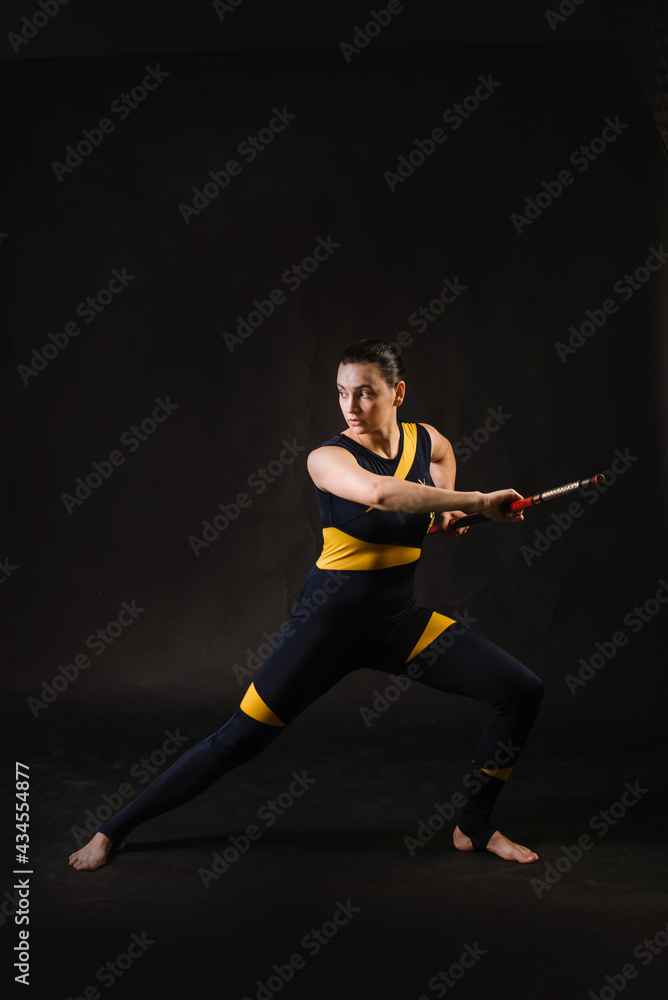 Horting sports woman with stick doing different stance on black background