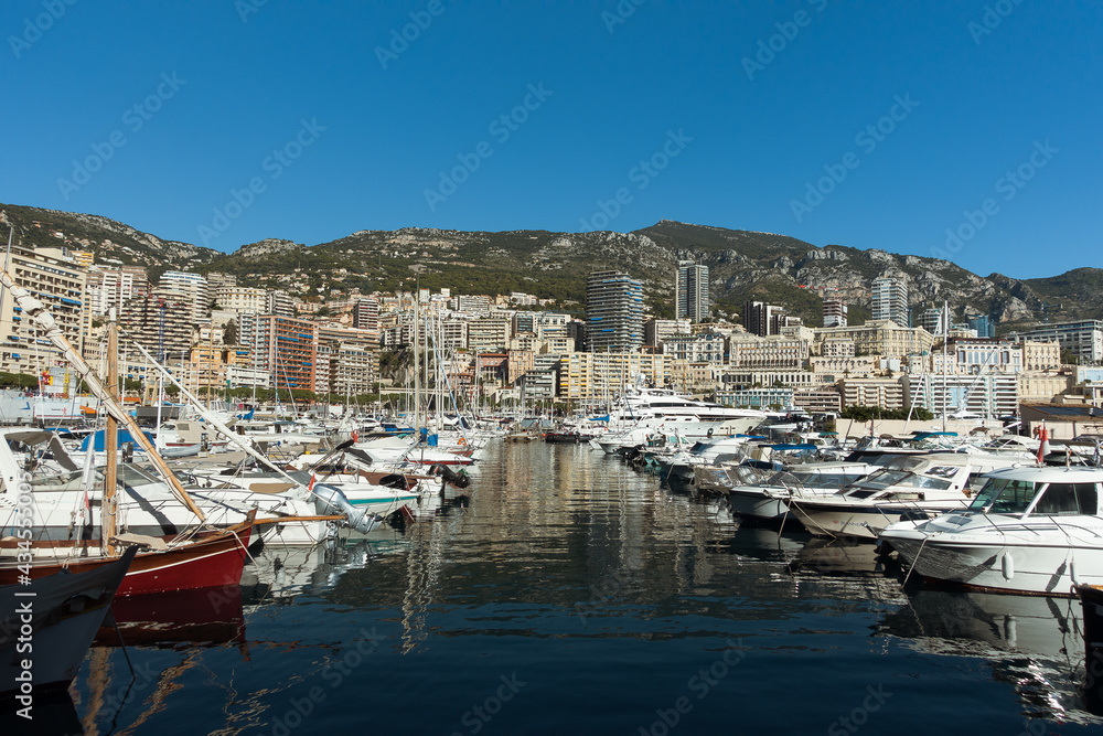 Luxury yachts in the Monaco harbor with large apartment complexes on background. Mediterranean yacht marina in Monaco sea port, Monaco and Monte Carlo principality. High quality photo