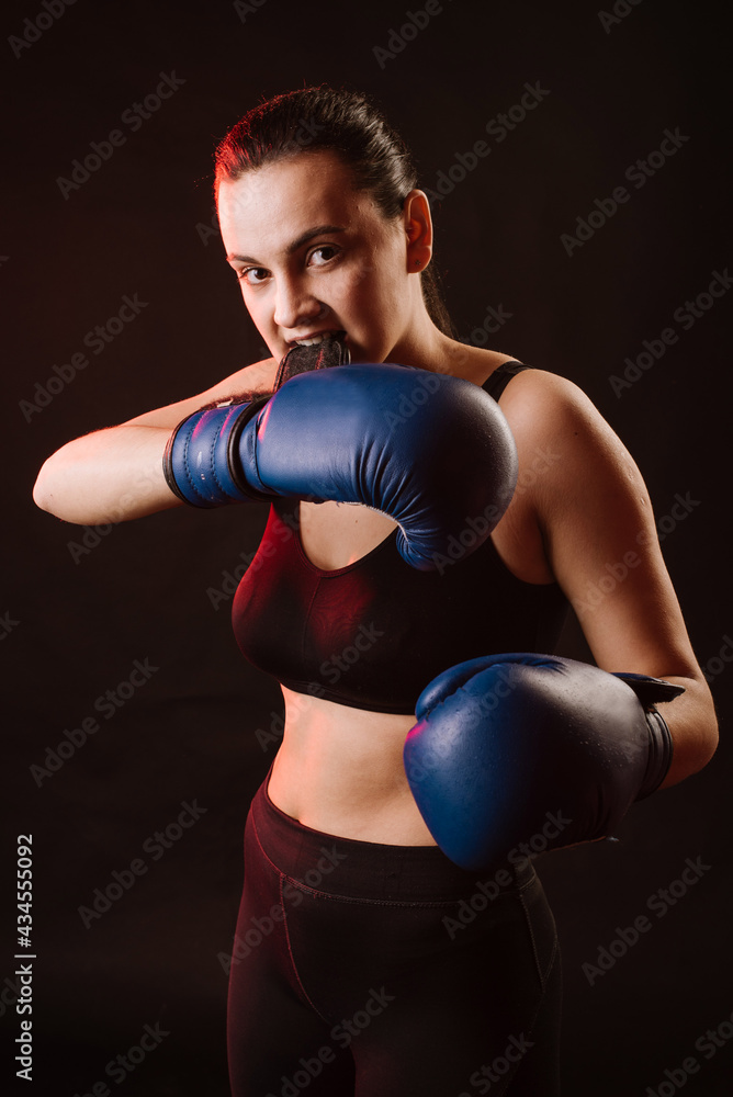 Boxer woman wearing gloves and preparing for battle on dark background