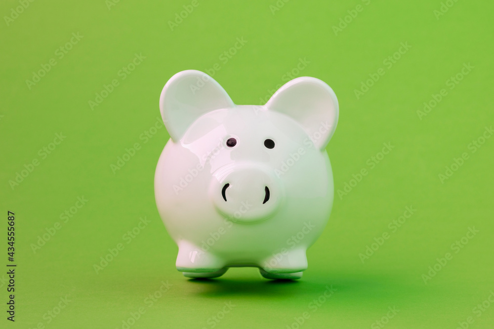 White ceramic piggy bank on green background