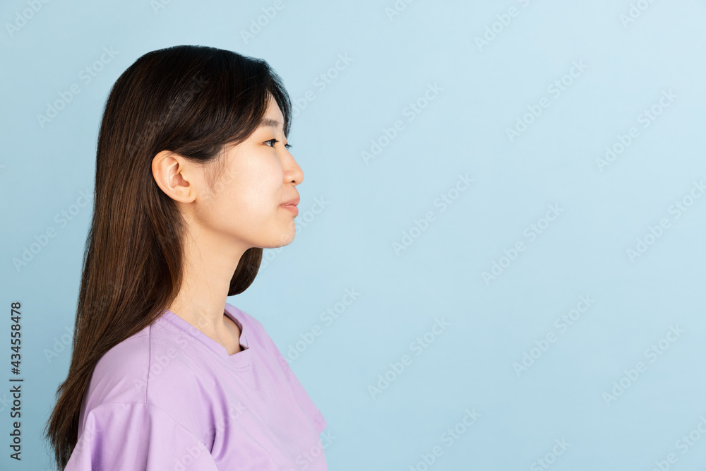 Asian young woman's portrait on blue studio background. Concept of human emotions, facial expression, youth, sales, ad. Asian young woman's portrait on blue studio background. Concept of human emotions, facial expression, youth, sales, ad.