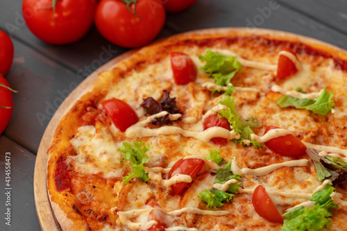Close up of freshly baked pizza on black wooden table