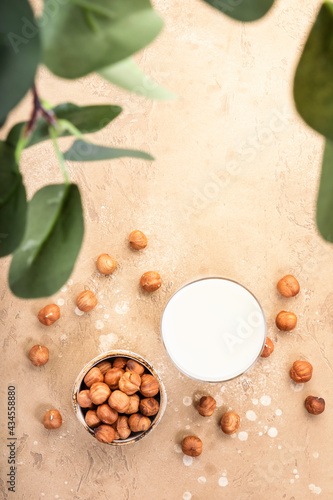 Hazelnut nut milk in glass beige table background. Non dairy alternative vegan milk. Healthy vegetarian diet food and drink