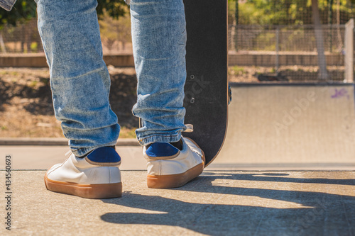 Detail shot of the feet of a teenage skater, about to go down the ramp of the skate park,