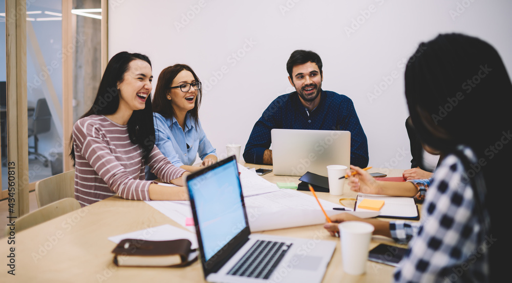 Laughing colleagues with laptops talking during workday Laughing colleagues with laptops talking during workday