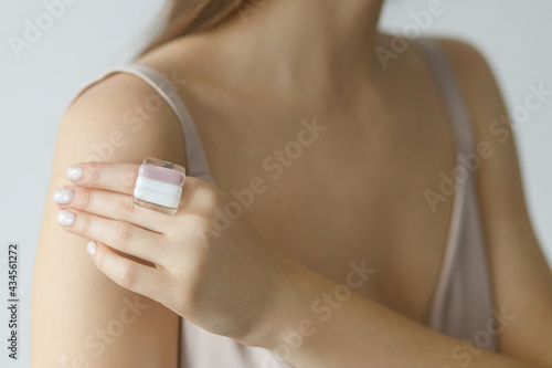 Beautiful stylish sensual woman with modern square pink ring on hand and white manicure, closeup. Fashionable female in pastel pink dress with unusual fused glass accessory.Beauty and care