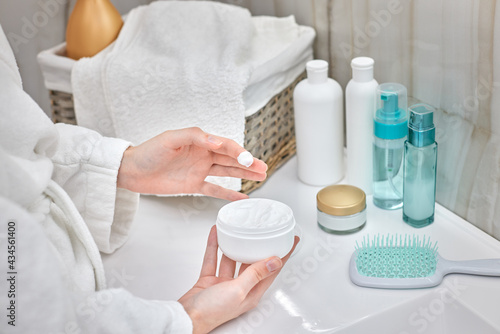 female hand holding jar with a cosmetic cream