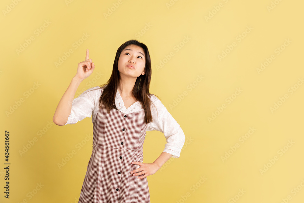 Asian young woman's portrait on yellow studio background. Concept of human emotions, facial expression, youth, sales, ad. Asian young woman's portrait on yellow studio background. Concept of human emotions, facial expression, youth, sales, ad.