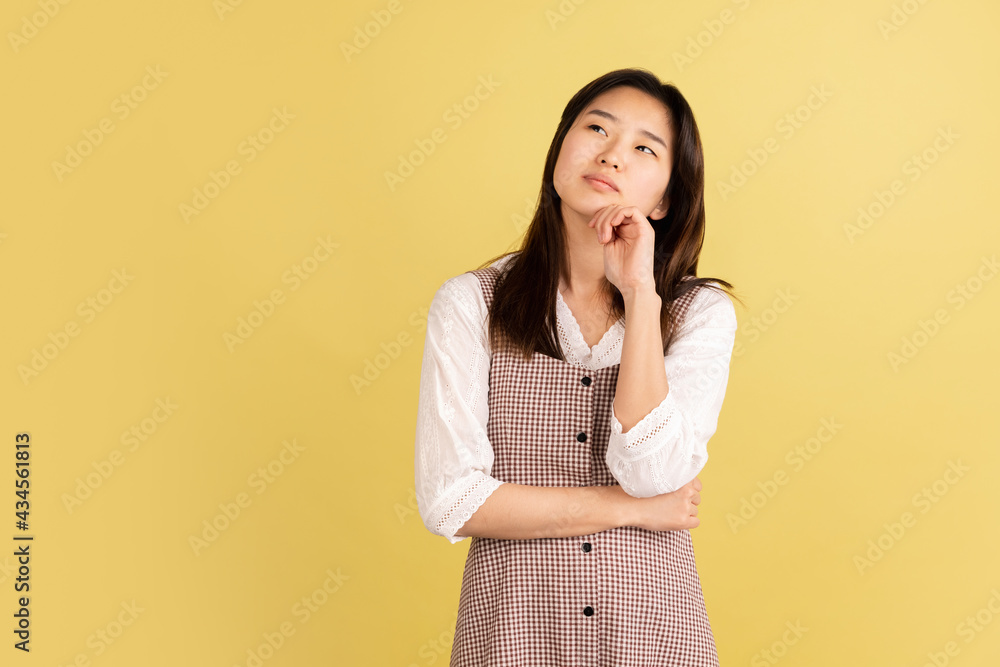 Asian young woman's portrait on yellow studio background. Concept of human emotions, facial expression, youth, sales, ad. Asian young woman's portrait on yellow studio background. Concept of human emotions, facial expression, youth, sales, ad.