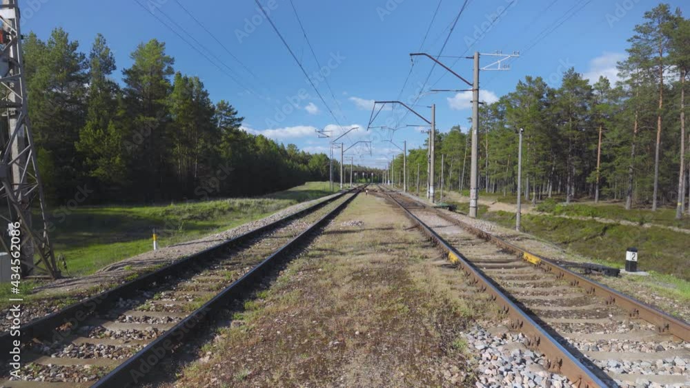 Railway rails and sleepers on embankments with stones. Sunny spring day in Latvia. Pine forest with green crowns. Railway rails and sleepers on embankments with stones. Sunny spring day in Latvia. Pine forest with green crowns.