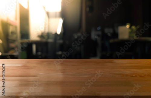 Empty wooden table top with lights bokeh on blur restaurant background.