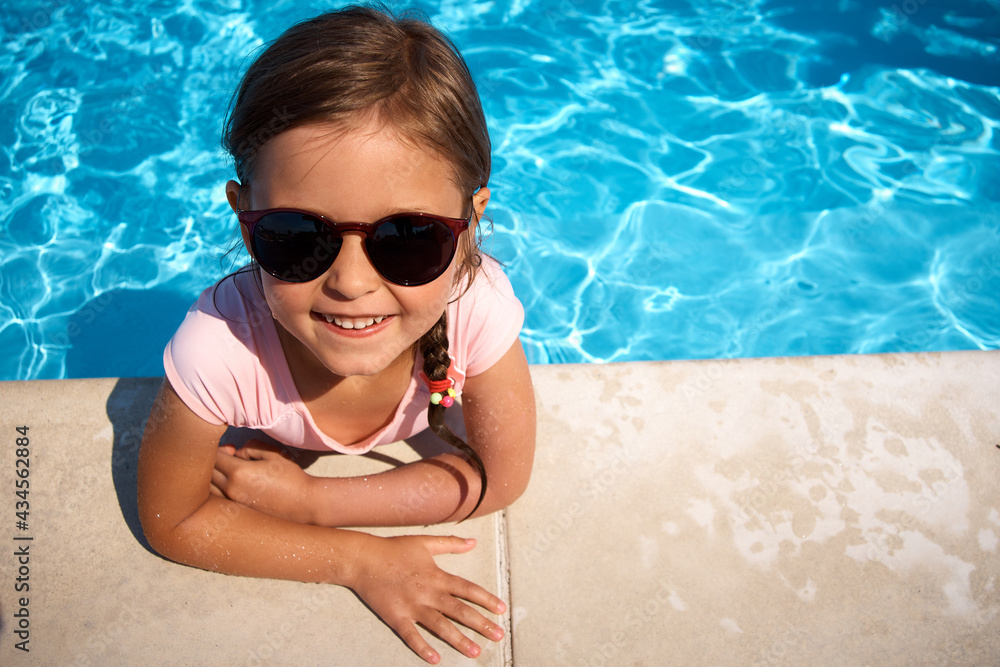 Happy little girl by the pool. Summer vacation.