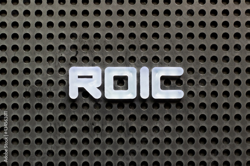 White color letter in word ROIC (Abbreviation of Return on invested capital) on black pegboard background