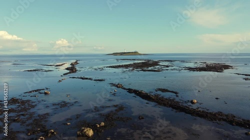 Aerial view of Pladda Lighthouse on the Isle of Arran on a sunny day, Scotland. Flying towards the lighthouse over the sea. photo