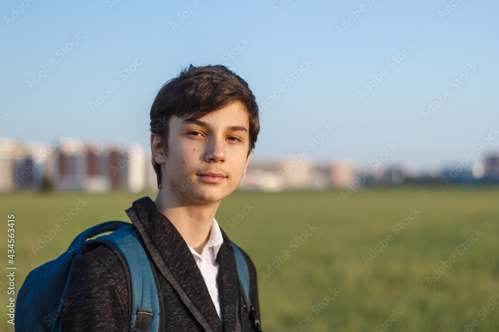 School teenager waiting for a school bus, on his way to school. On the way home from school against the background of the urban landscape School teenager waiting for a school bus, on his way to school. On the way home from school against the background of the urban landscape
