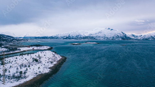 Breathtaking bird's eye view of fjord mountains covered with snow in winter. Aerial top view of scenery rock peaks, picturesque beautiful nature landscape. Lofoten Island surrounds by Nordic sea © BullRun