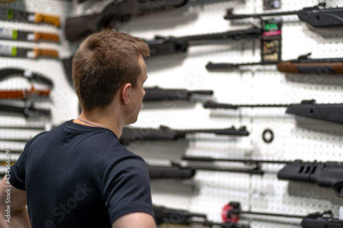 A man in a gun store looking at a rifle