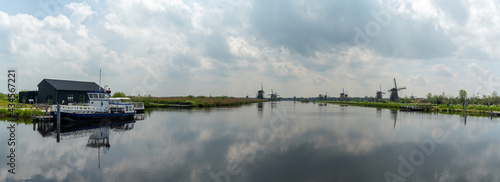 panorama view of the windmills and canals of Kinderdijk in South Holland with a dock and boat in the foreground photo