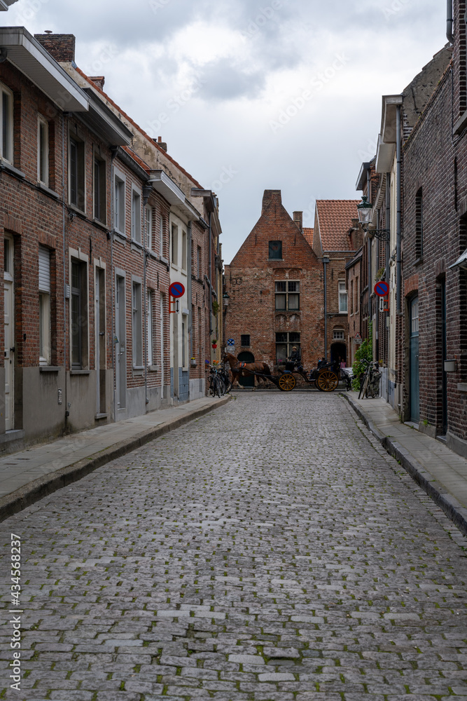 picturesque historic brick buildings typical of the old city center of Bruges with a horse and carriage in the background