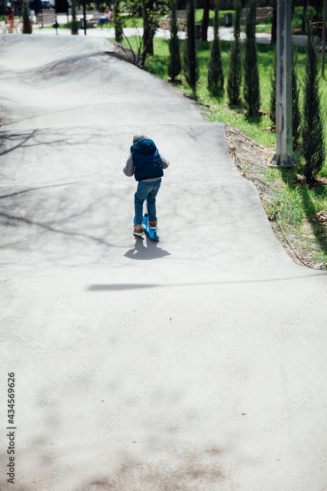 Little boy rides a scooter on the roads in the playground Little boy rides a scooter on the roads in the playground