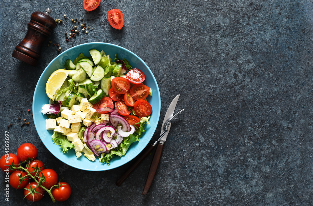Mix salad with vegetables, leaves and feta. Greek salad in a plate on a blue concrete background. View from above. Mix salad with vegetables, leaves and feta. Greek salad in a plate on a blue concrete background. View from above.