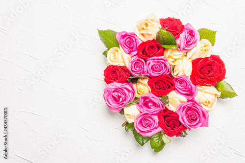 Composition of fresh multicolored roses on ceramic stand