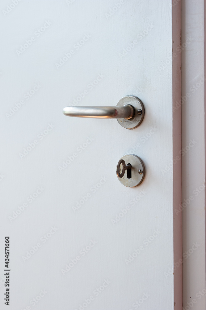 Metal door lock handle and key on wooden white interior door isolated close up shot Metal door lock handle and key on wooden white interior door isolated close up shot