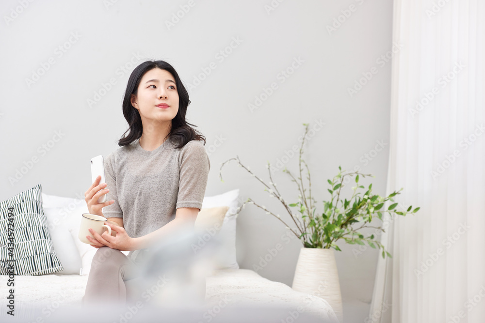 Asia Korean woman sitting on the bed. reading a book or cup of a tea Asia Korean woman sitting on the bed. reading a book or cup of a tea