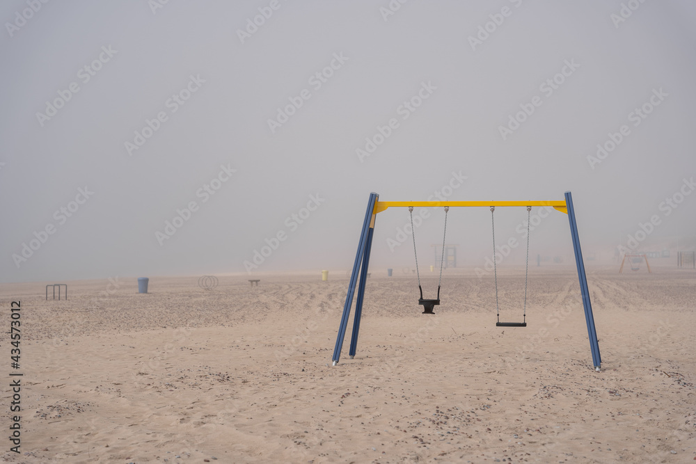 The beach of the Baltic Sea in Ventspils where there are various swings and other attractions is in thick fog The beach of the Baltic Sea in Ventspils where there are various swings and other attractions is in thick fog