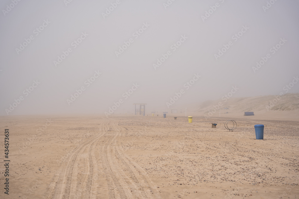 Baltic Sea beach in Ventspils covered with thick fog, garbage cans and benches in the distance Baltic Sea beach in Ventspils covered with thick fog, garbage cans and benches in the distance