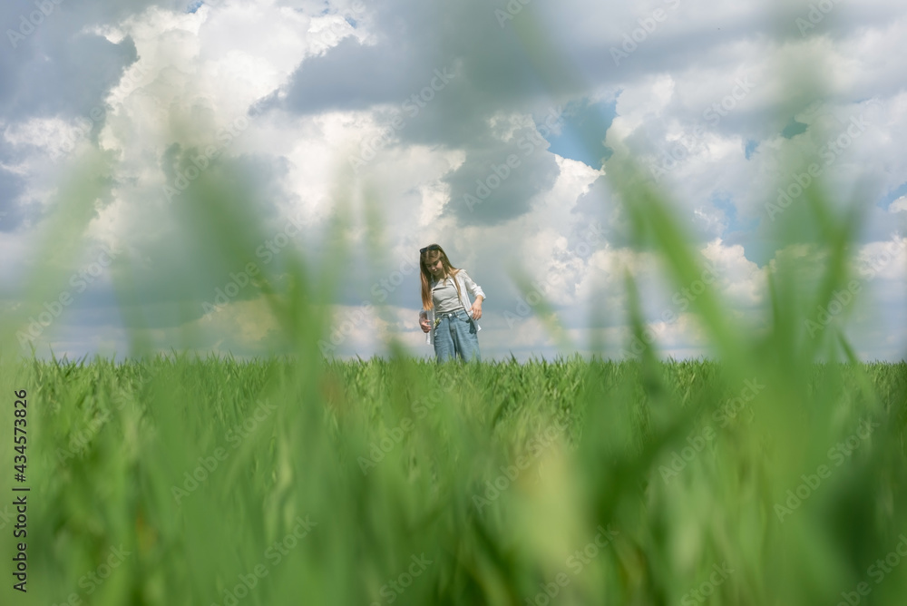 teenage girl in green grass, in the field, against the backdrop of a cloudy sky teenage girl in green grass, in the field, against the backdrop of a cloudy sky