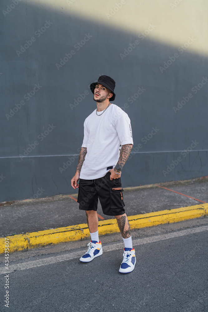 Chico joven atletico posando con ropa urbana en entornos de ciudad